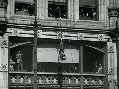 Harry Houdini hangs suspended upside-down over a street in a Straitjacket © McCord Stewart Museum, 2022.